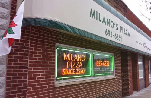 Exterior of a brick building with a sign that says Milano's Pizza