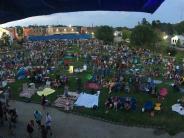 Large crowd of people in front of bandshell at twilight