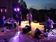 Band performing on a stage, bathed in purple light