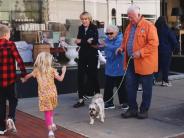 Older couple walking a dog and exhanging friendly wave with a woman and two children