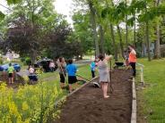 Children around a freshly tilled plant bed in a community garden