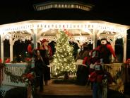 Image of a gazebo at night, decorated for Christmas with lights toy carolers 