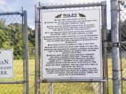 sign that says 'rules' attached to chain link fence at dog park