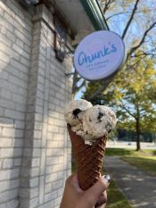 hand holding an ice cream cone in front of a sign that reads chunks