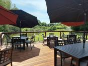 an outdoor deck with chairs, tables and umbrellas in summer