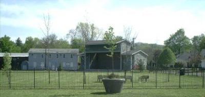 A large green lawn with a metal fence around it, and an outdoor stage on the far side