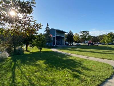 Blue bandshell in front of open green space and trees