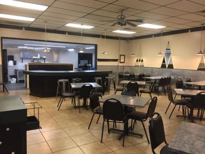 Interior of a restaurant featuring an order window, black tables and chairs