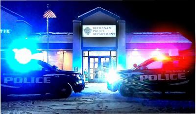 Two police vehicles with their lights on in front of the police station at night.