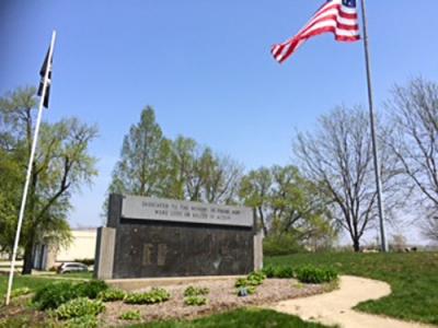 Granite memorial sign next to American and POWMIA flags