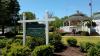 White Gazebo in background, green sign that says Buchanan Garden Club Memorial Garden in foreground 